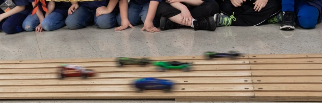 Young children racing pinewood cars action shot